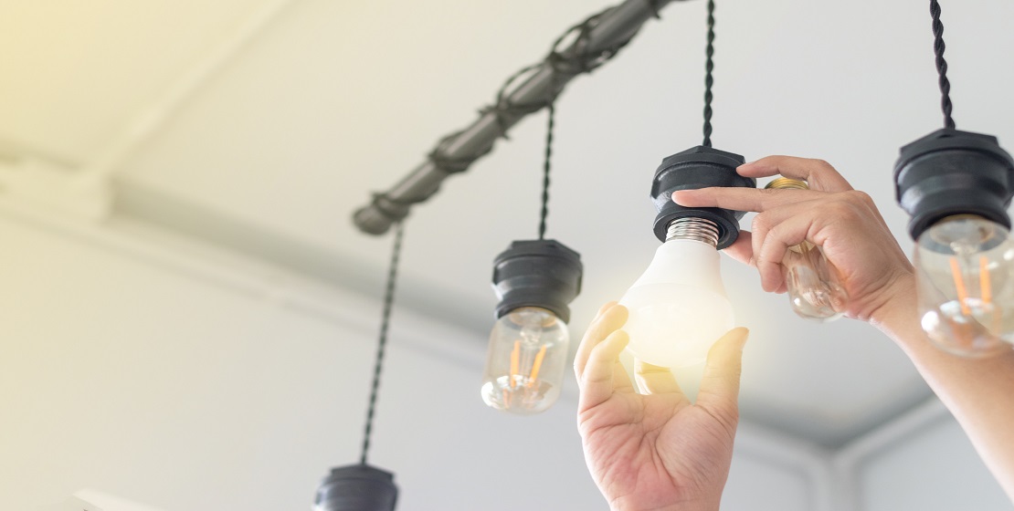 LED light Power saving concept. Asia man changing compact-fluorescent (CFL) bulbs with new bulb. A $5 Trillion Idea to Save Energy is Hiding in Plain Sight give content